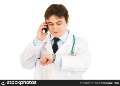 Medical doctor talking on mobile and looking at his watch isolated on white&#xA;