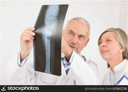 Medical doctor team senior man with female colleague look x-ray