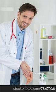 medical doctor using sanitizer dispenser in clinic