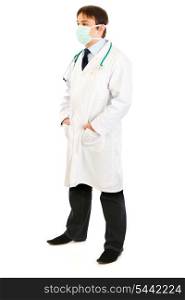 Medical doctor with mask on face and hands in pockets isolated on white&#xA;
