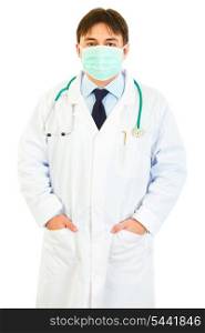 Medical doctor with mask on face holding hands in pockets isolated on white&#xA;