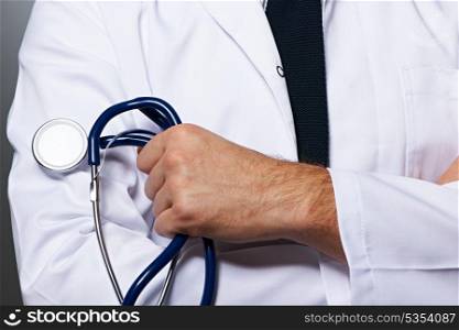 Medical doctor with stethoscope against grey background