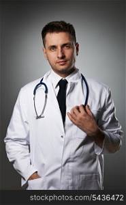 Medical doctor with stethoscope portrait against grey background