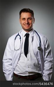 Medical doctor with stethoscope portrait against grey background
