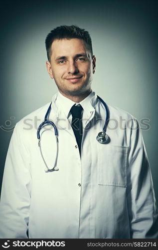 Medical doctor with stethoscope portrait against grey background