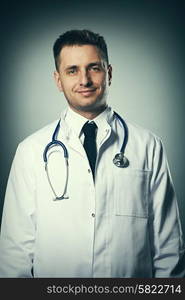 Medical doctor with stethoscope portrait against grey background