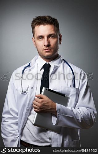 Medical doctor with tablet pc portrait against grey background
