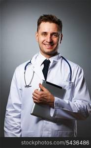 Medical doctor with tablet pc portrait against grey background