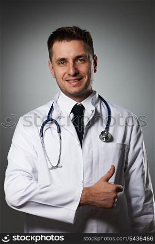 Medical doctor with thumb up portrait against grey background