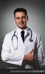 Medical doctor with thumb up portrait against grey background