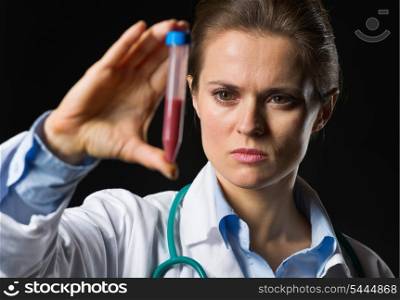 Medical doctor woman looking on test tube with blood isolated on black
