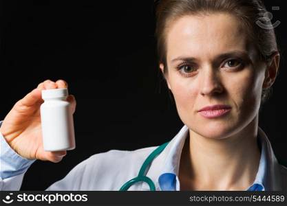 Medical doctor woman showing medicine bottle on black background