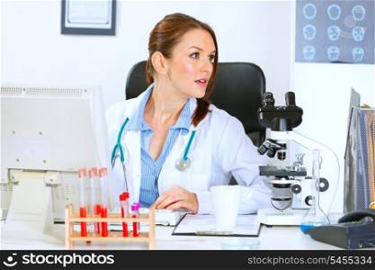 Medical doctor woman sitting at office table and looking away&#xA;