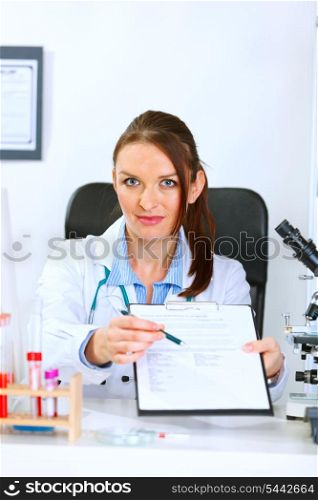 Medical doctor woman sitting at office table with document and pen for signing &#xA;