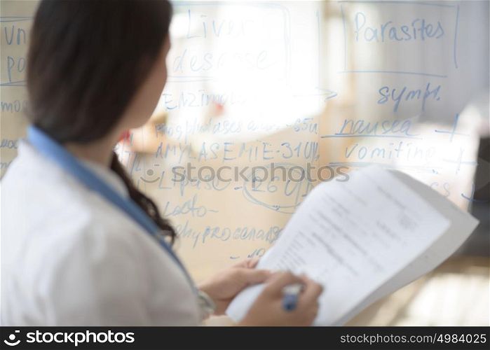 Medical doctor writing patient test results on transparent board to diagnose