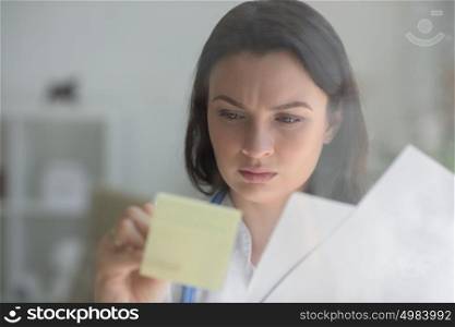 Medical doctor writing patient test results on transparent board to diagnose disease of her patient