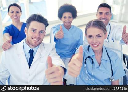 medical education, health care, gesture people and medicine concept - group of happy doctors on seminar in lecture hall at hospital showing thumbs up