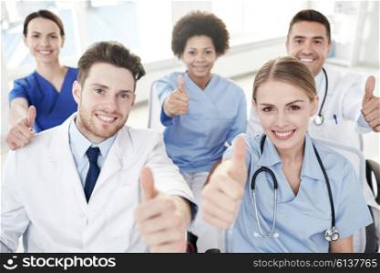 medical education, health care, gesture people and medicine concept - group of happy doctors on seminar in lecture hall at hospital showing thumbs up