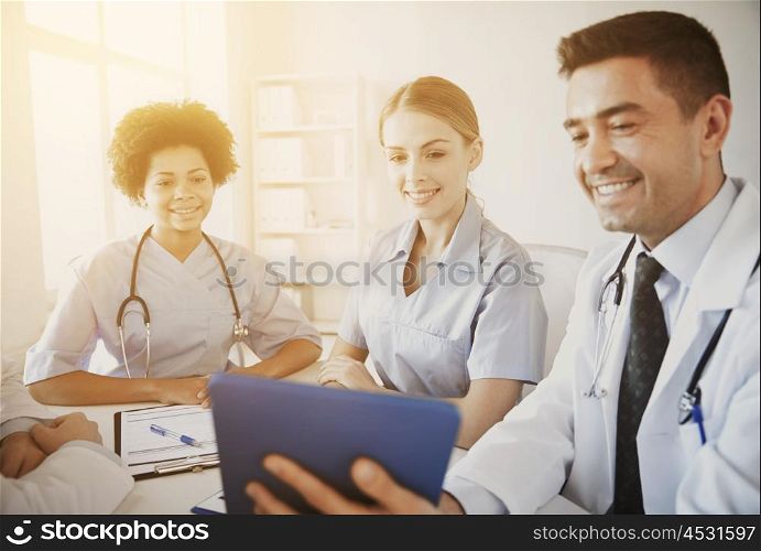 medical education, health care, people, technology and medicine concept - group of happy doctors with tablet pc computer meeting at medical office