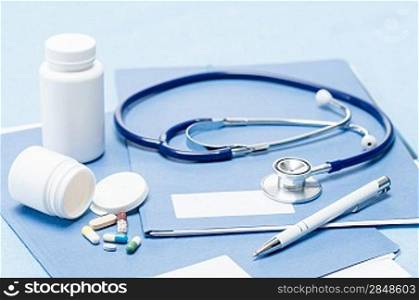 Medical equipment stethoscope, pen and medication over documents