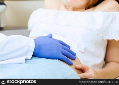 Medical examination. Young pregnant woman examined by doctor at hospital