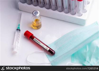 medical face bask a blood tube with positive Coronavirus 2019-nCoV Blood Sample.. Coronavirus Blood Sample