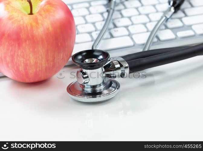 Medical health care concept with traditional stethoscope and apple with computer keyboard in background