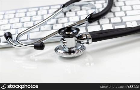 Medical health care concept with traditional stethoscope and computer keyboard in background
