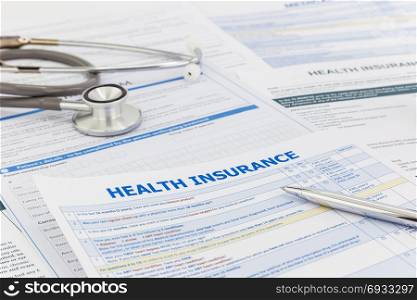 Medical insurance questionnaire, silver premium pen and clinical stethoscope. Healthcare survey and insurance information concepts.