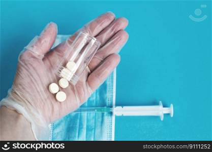 medical mask, syringe and tablets close on the blue background. Coronavirus, flu, respiratory disease concept. Horizontal orientation. Top view.. medical mask, syringe and tablets close on the blue background. hand holds pills. Coronavirus, flu
