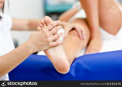 Medical massage at the foot in a physiotherapy center. Female physiotherapist inspecting her patient.