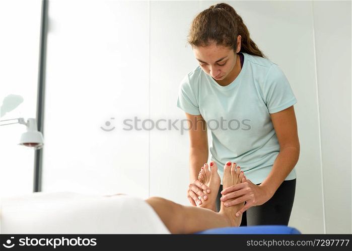 Medical massage at the foot in a physiotherapy center. Female physiotherapist inspecting her patient.. Medical massage at the foot in a physiotherapy center.