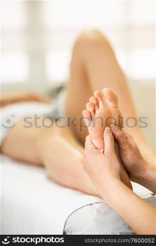 Medical massage at the foot in a physiotherapy center. Female physiotherapist inspecting her patient.. Medical massage at the foot in a physiotherapy center