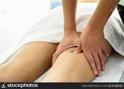 Medical massage at the leg in a physiotherapy center. Female physiotherapist inspecting her patient.