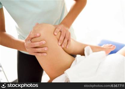Medical massage at the leg in a physiotherapy center. Female physiotherapist inspecting her patient. Close-up photograph.