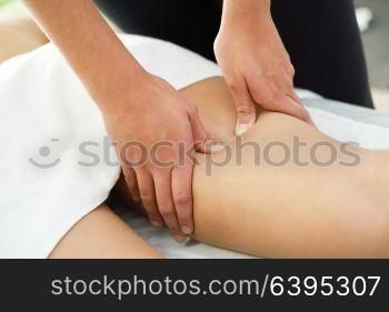 Medical massage at the leg in a physiotherapy center. Female physiotherapist inspecting her patient.