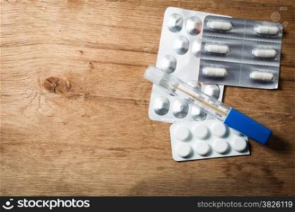 Medical. Packages of pills tablets drugs and mercury thermometer on wooden background. Pharmacy.