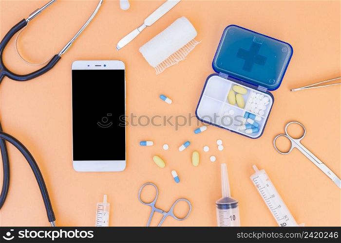 medical pill box stethoscope mobile phone medical equipment s orange background