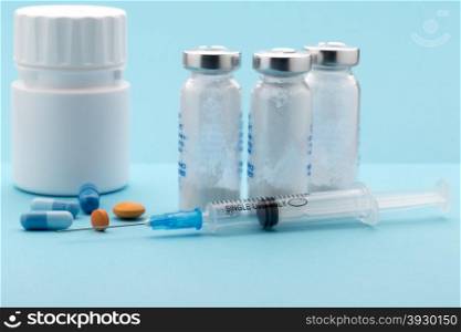 Medical pills bottle and injection syringe. Medical pills bottle and injection syringe on blue background