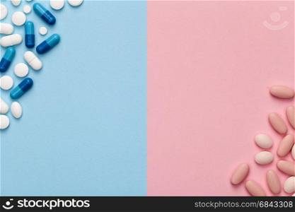 Medical pills for man and woman on blue and pink background. Copy space. Top view