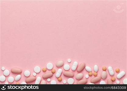 Medical pills for woman on pink background. Copy space. Top view