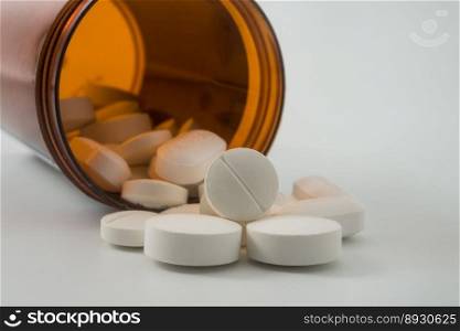 Medical pills spilling out of a toppled from pill bottle