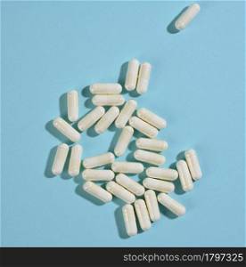 medical powder in white capsules on a blue background. Treatment pills, nutritional supplements