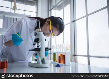Medical Research and Scientists are working with a microscope and a tablet and Test Tubes, Micropipette and Analysis Results in a laboratory.
