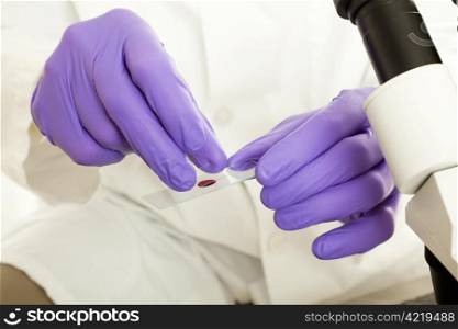 Medical researcher preparing a slide with a sample of blood.