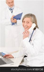 Medical senior doctor female calling with professional male colleague office