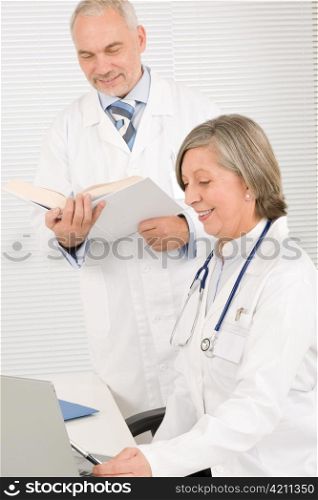 Medical senior doctor female look computer with professional male colleague