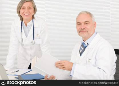Medical senior doctor male reading book with professional female colleague