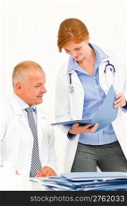 Medical senior doctor male with young female colleague look folder