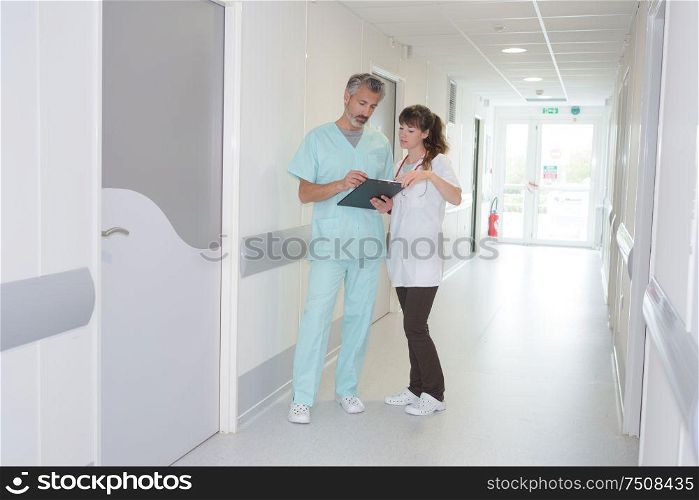 medical staff looking at clipboard in hospital corridor
